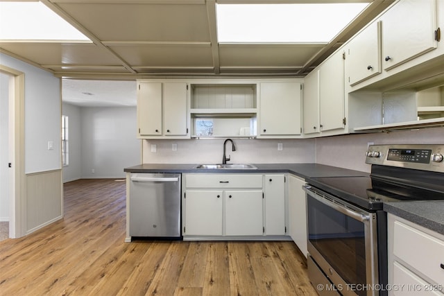 kitchen with open shelves, dark countertops, stainless steel appliances, and a sink