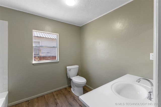 full bath with baseboards, toilet, wood finished floors, a textured ceiling, and a sink