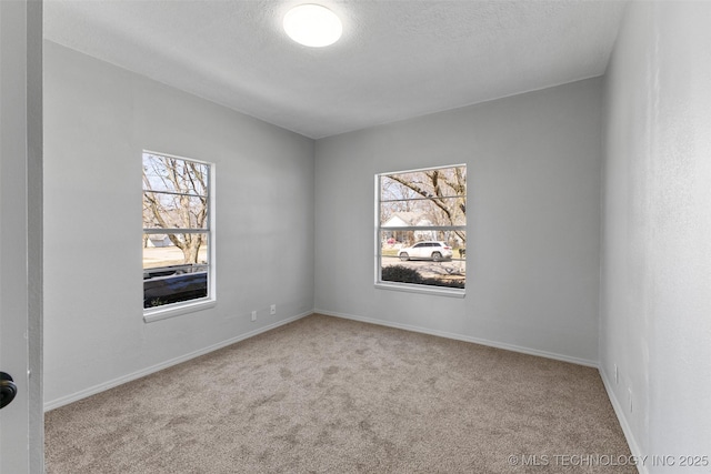 spare room featuring a textured ceiling, baseboards, and carpet flooring