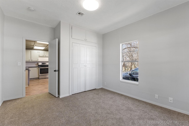 unfurnished bedroom with a closet, light carpet, visible vents, and baseboards