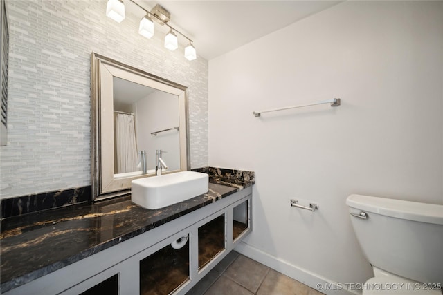 full bath with toilet, vanity, baseboards, and tile patterned floors