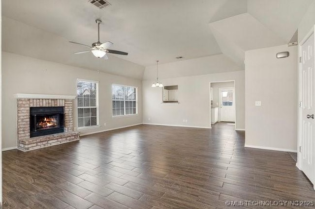 unfurnished living room featuring baseboards, lofted ceiling, dark wood-style floors, a fireplace, and ceiling fan with notable chandelier