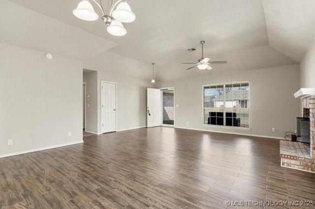 unfurnished living room with ceiling fan with notable chandelier, vaulted ceiling, a fireplace, and wood finished floors