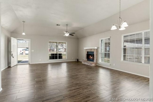 unfurnished living room with dark wood finished floors, lofted ceiling, a brick fireplace, baseboards, and ceiling fan with notable chandelier