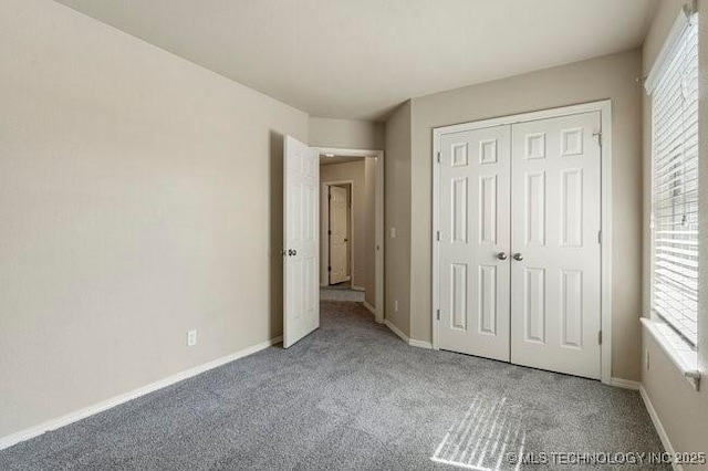 unfurnished bedroom featuring carpet, baseboards, and a closet