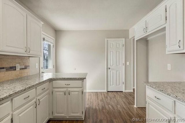 kitchen featuring a peninsula, decorative backsplash, white cabinets, and dark wood-type flooring