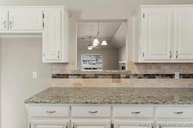 kitchen with light stone countertops, white cabinetry, and backsplash