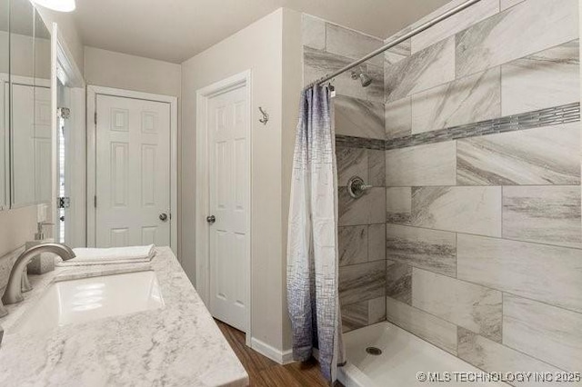 bathroom featuring a tile shower, wood finished floors, and a sink