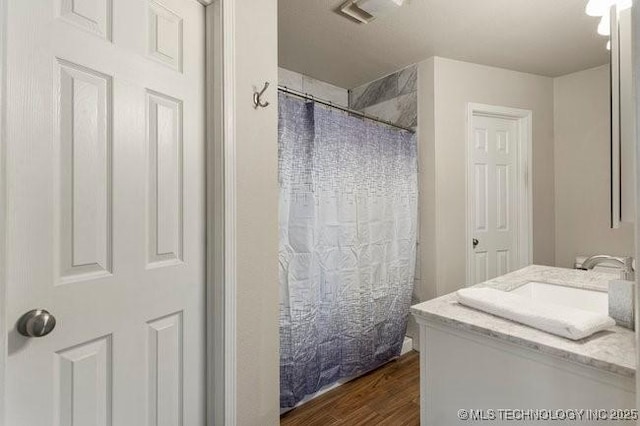 full bathroom featuring a shower with shower curtain, visible vents, wood finished floors, and vanity