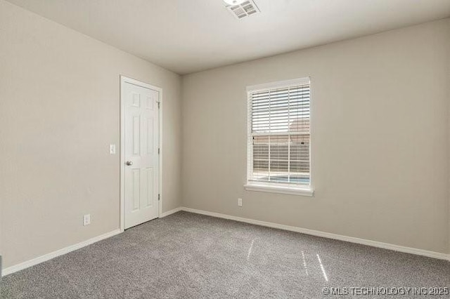 carpeted spare room featuring visible vents and baseboards