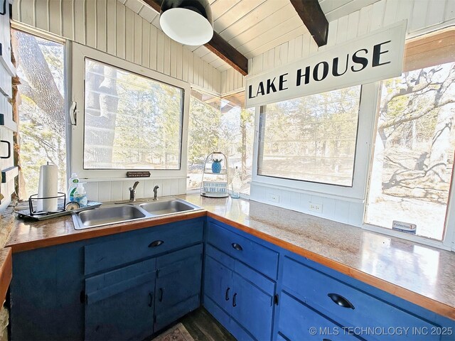 kitchen with vaulted ceiling with beams, blue cabinetry, a sink, and wood ceiling