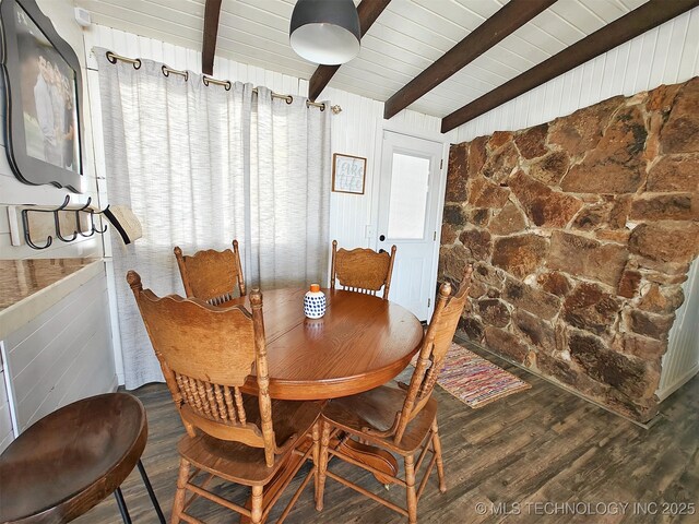 dining room with wooden walls, wooden ceiling, lofted ceiling with beams, and wood finished floors