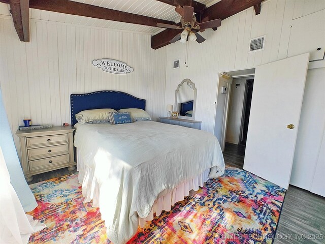 bedroom with a ceiling fan, visible vents, beamed ceiling, and wood finished floors