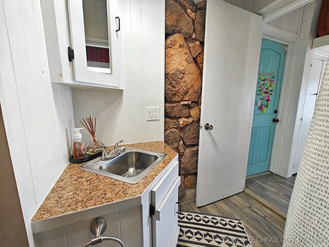 kitchen with dark wood-style flooring, light countertops, glass insert cabinets, white cabinetry, and a sink