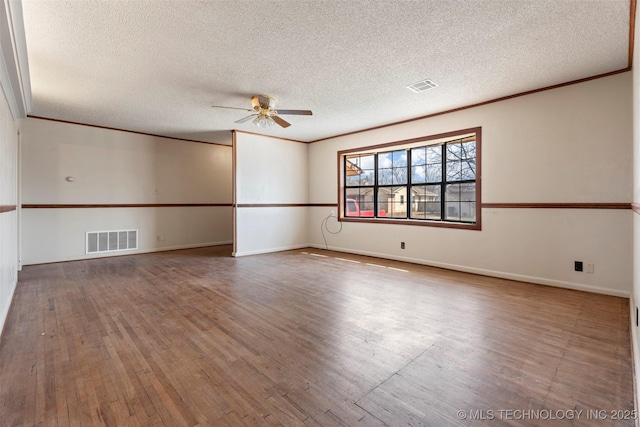 spare room featuring wood-type flooring, visible vents, and crown molding