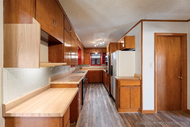 kitchen featuring brown cabinets, light countertops, backsplash, stainless steel oven, and wood finished floors