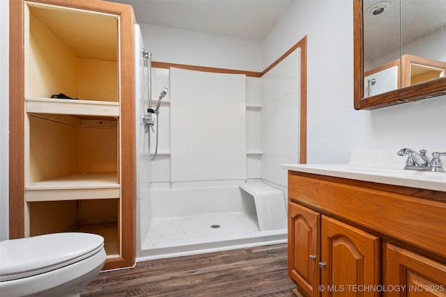 full bathroom featuring vanity, wood finished floors, toilet, and a shower stall