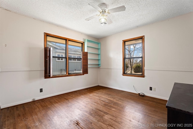 spare room with a textured ceiling, wood-type flooring, a ceiling fan, and baseboards