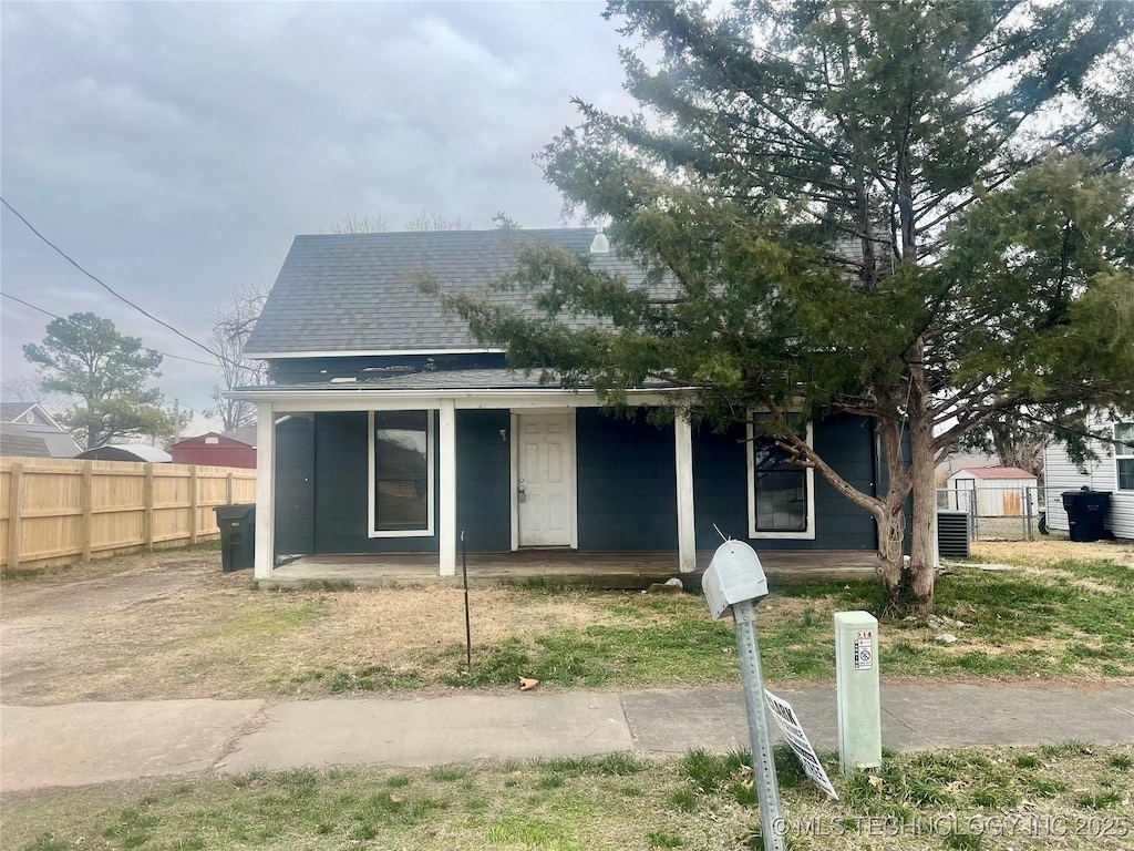 bungalow-style home featuring a shingled roof, covered porch, and fence