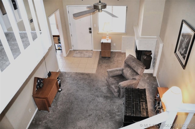 carpeted living area with ceiling fan, a fireplace, baseboards, and tile patterned floors