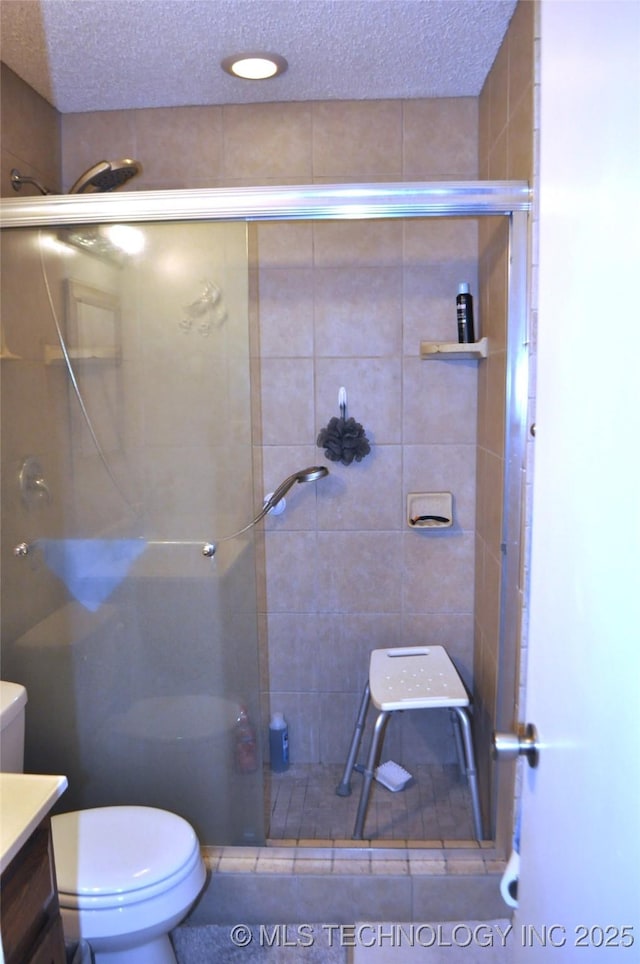 bathroom featuring toilet, a shower stall, a textured ceiling, and vanity