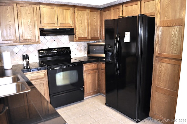 kitchen featuring light tile patterned floors, dark countertops, decorative backsplash, under cabinet range hood, and black appliances