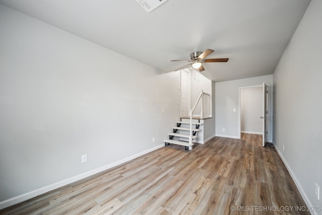 unfurnished room with ceiling fan, wood finished floors, visible vents, baseboards, and stairs