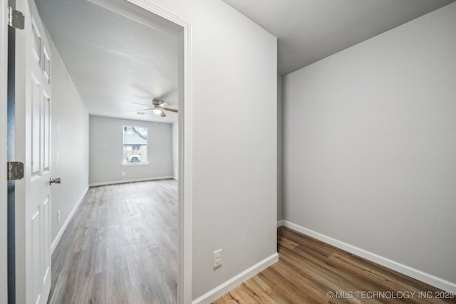 empty room featuring ceiling fan, baseboards, and wood finished floors