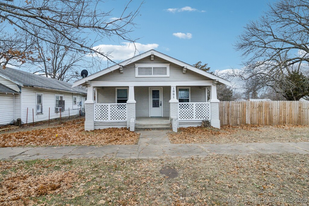 1001 S Armstrong Ave, Bartlesville, OK 74003 - view of front of property featuring covered porch, brick siding, and fence