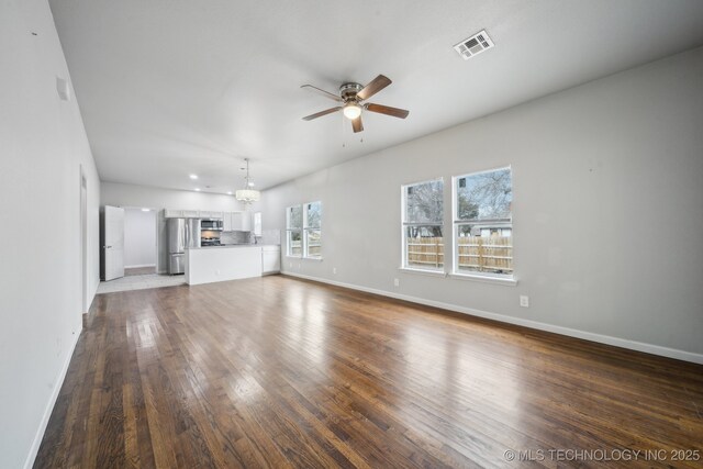 unfurnished living room with baseboards, visible vents, hardwood / wood-style floors, and ceiling fan with notable chandelier