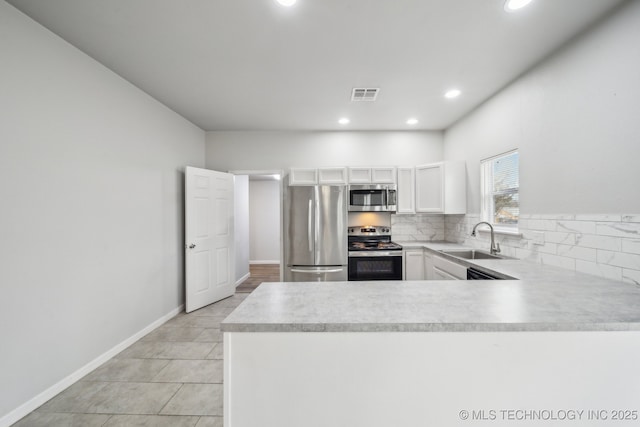 kitchen with stainless steel appliances, light countertops, visible vents, a sink, and a peninsula