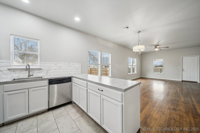 kitchen with pendant lighting, light countertops, a sink, dishwasher, and a peninsula
