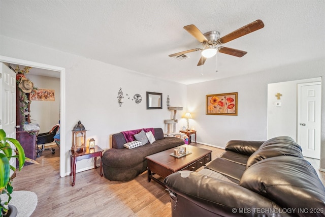 living area with ceiling fan, a textured ceiling, visible vents, and light wood-style floors