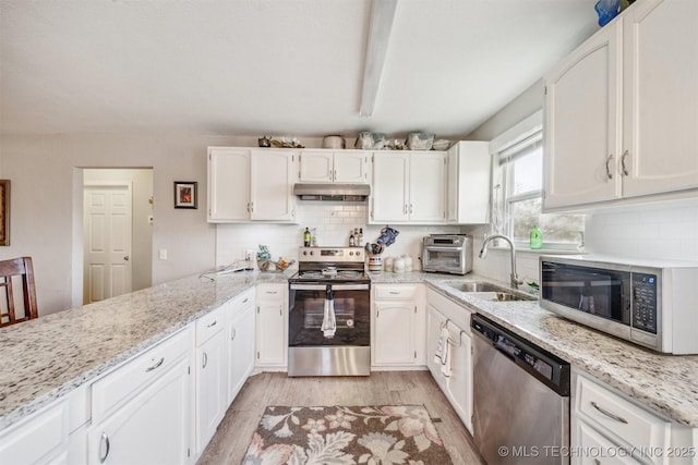 kitchen with appliances with stainless steel finishes, white cabinetry, a sink, and under cabinet range hood