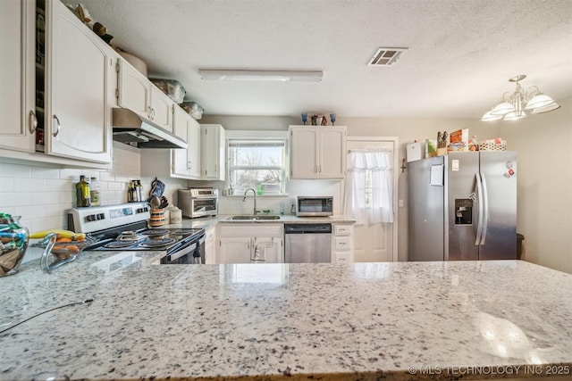 kitchen with visible vents, appliances with stainless steel finishes, light stone counters, under cabinet range hood, and a sink