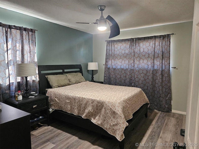 bedroom featuring ceiling fan, baseboards, and wood finished floors