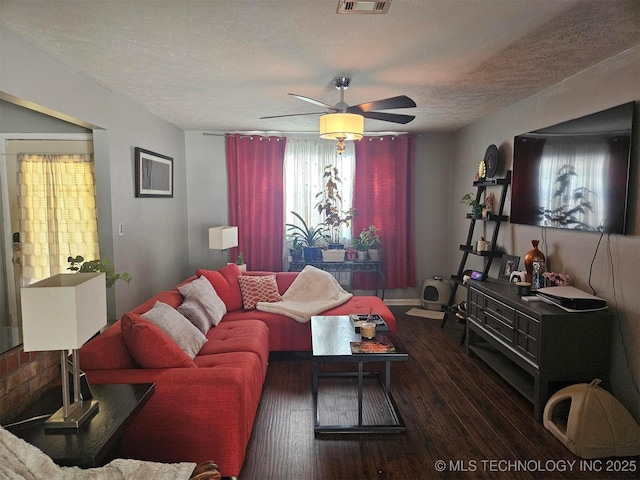 living area with a textured ceiling, hardwood / wood-style floors, visible vents, and a ceiling fan