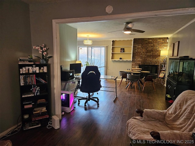 office space featuring wood finished floors, baseboards, built in features, a brick fireplace, and crown molding