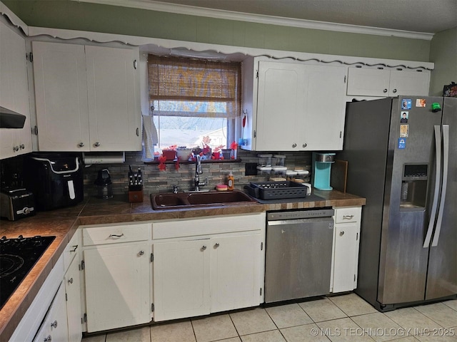 kitchen with white cabinets, a sink, stainless steel appliances, crown molding, and backsplash