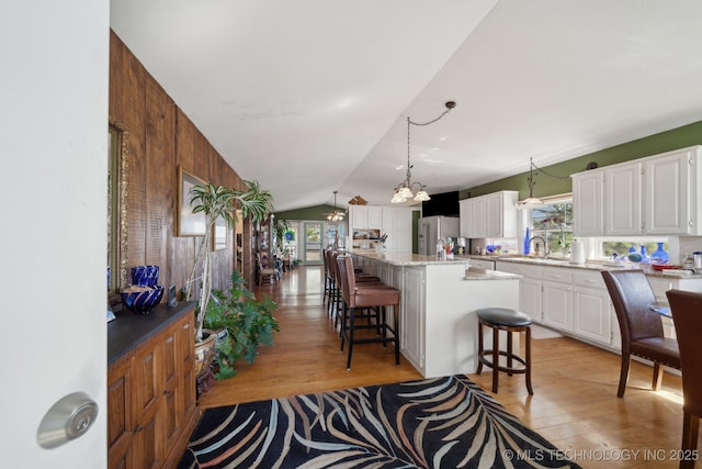 3126 E 490th Rd, Pryor, OK 74361 - kitchen featuring stainless steel fridge, light wood-style floors, a breakfast bar, and an inviting chandelier