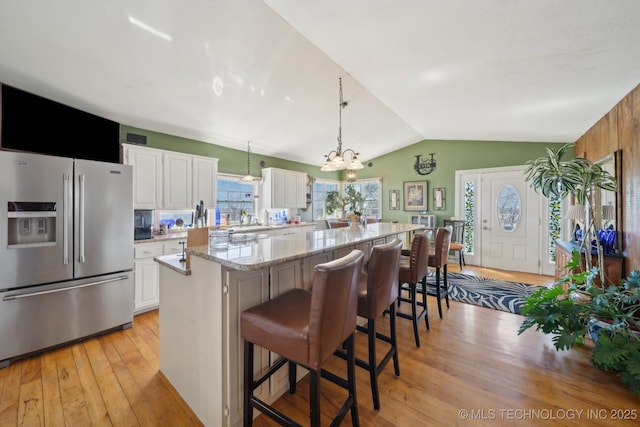 3126 E 490th Rd, Pryor, OK 74361 - kitchen with vaulted ceiling, white cabinets, light wood-style floors, a breakfast bar, and high end fridge