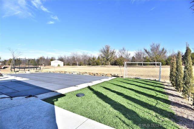 view of yard featuring a trampoline and an outbuilding