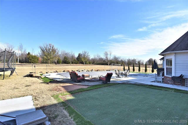 view of yard featuring a fire pit, a patio, and a trampoline