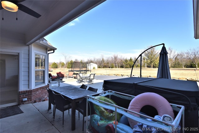 view of patio / terrace with a trampoline, outdoor dining space, and ceiling fan