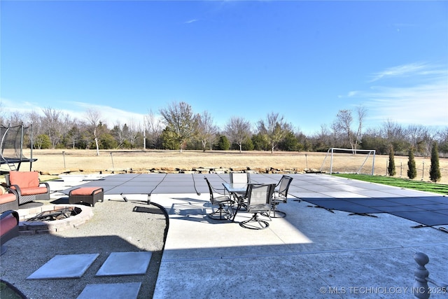 view of patio featuring a fenced in pool, a trampoline, and a fire pit