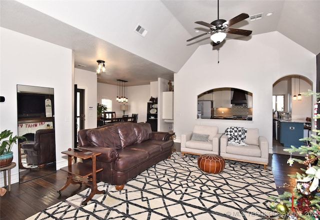 living area with a ceiling fan, arched walkways, visible vents, and wood finished floors