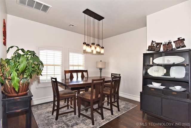 dining room featuring dark wood-type flooring, visible vents, and baseboards