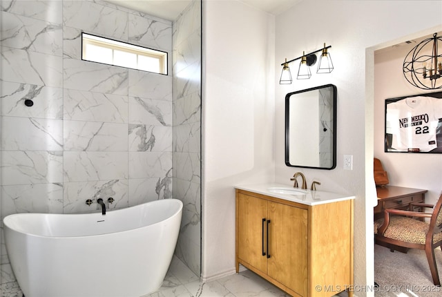 full bathroom with marble finish floor, a freestanding tub, and vanity