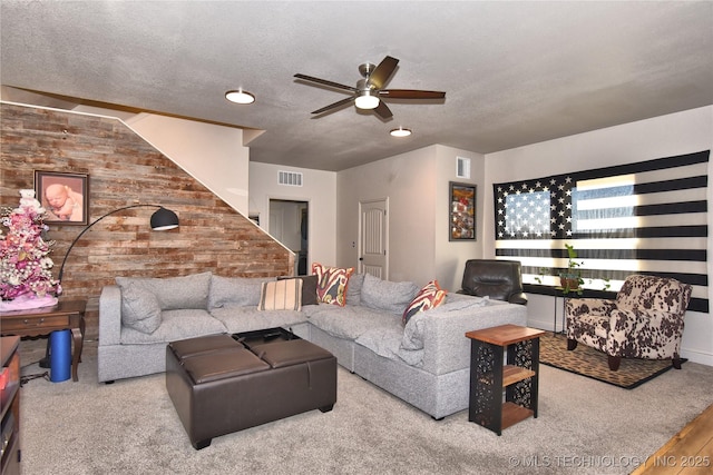 carpeted living room with a ceiling fan, visible vents, and a textured ceiling