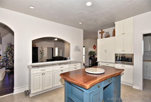 kitchen with blue cabinets, white cabinetry, butcher block counters, and stainless steel microwave